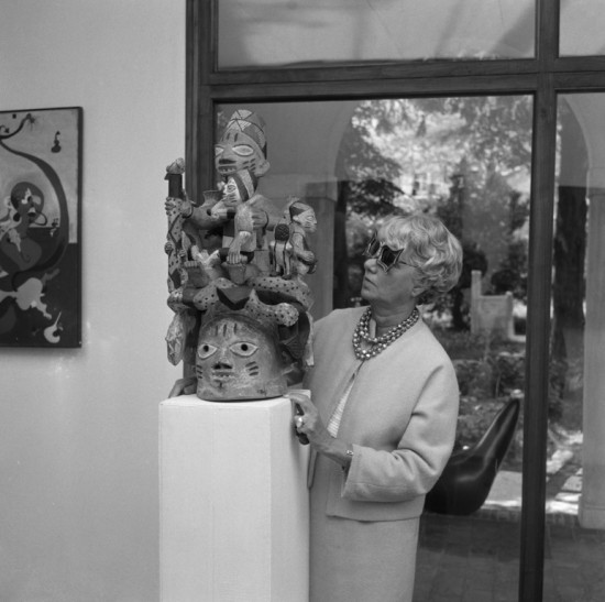 Peggy Guggenheim in the'barchessa' o fPalazzo Venier dei Leoni with her collection of African sculptures; Venice late 1960's